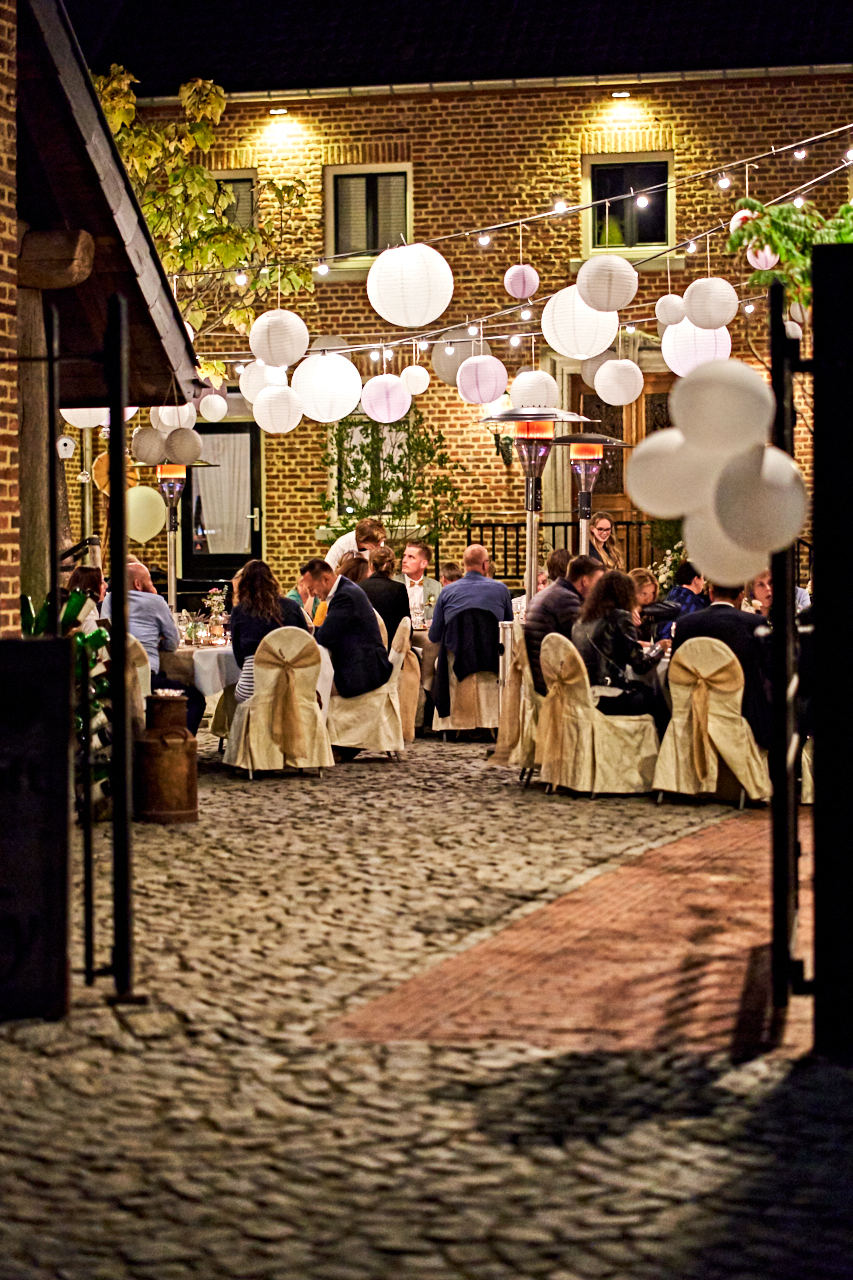 Evening setting of a dinner in a courtyard with fairy lights and lanterns