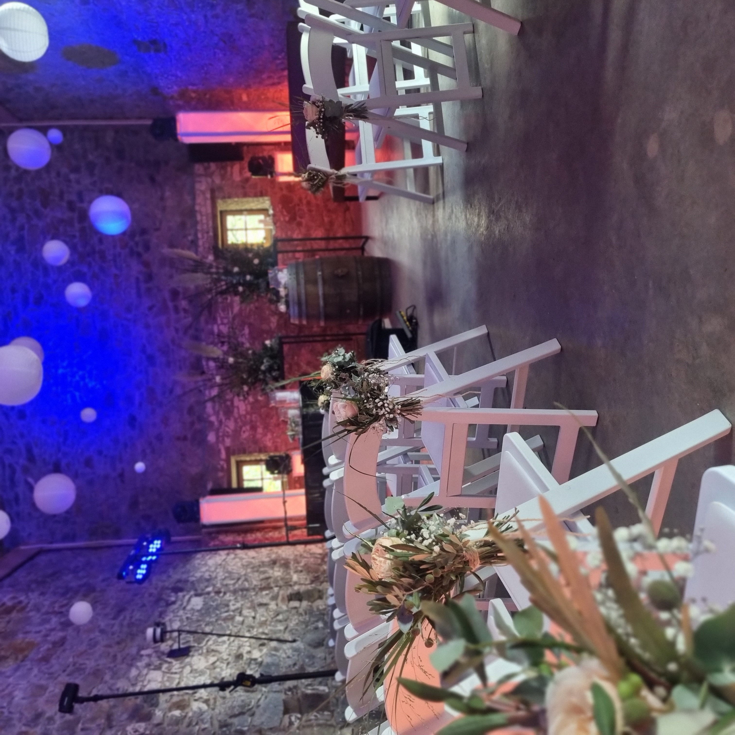 Stimmungsvolle Zeremonieräumlichkeit mit weißen Stühlen und rustikalen Wänden