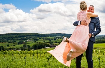 Bruidspaar omhelst elkaar in de wijngaard met heuvels op de achtergrond